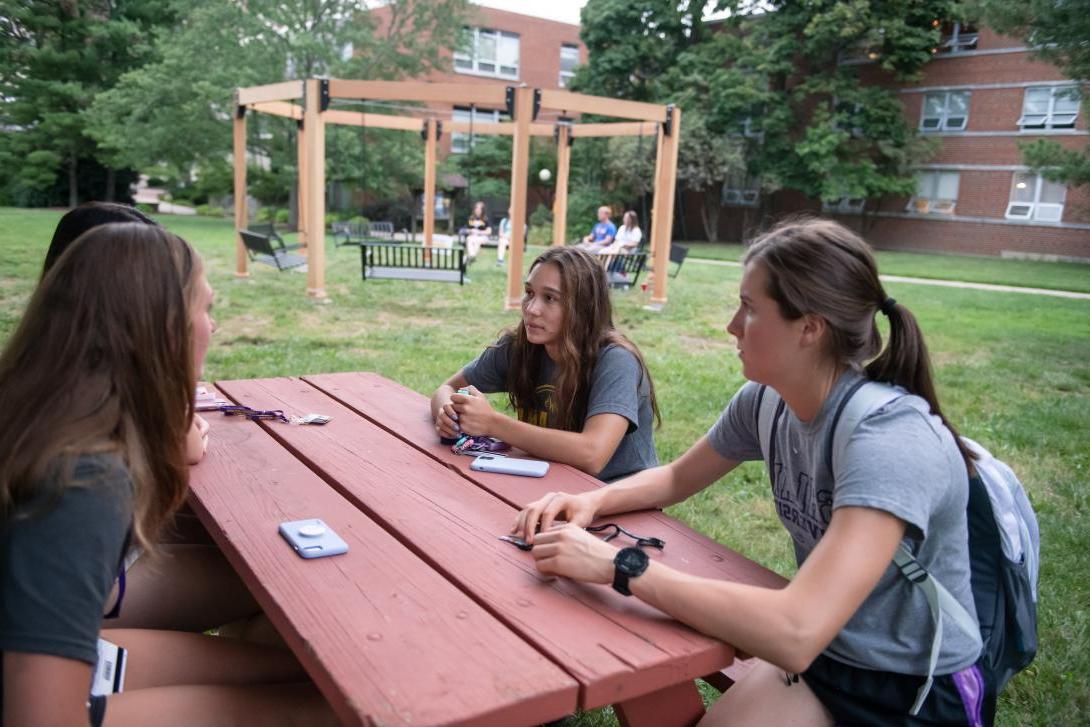 Honors students at ice cream social sitting at picnic table