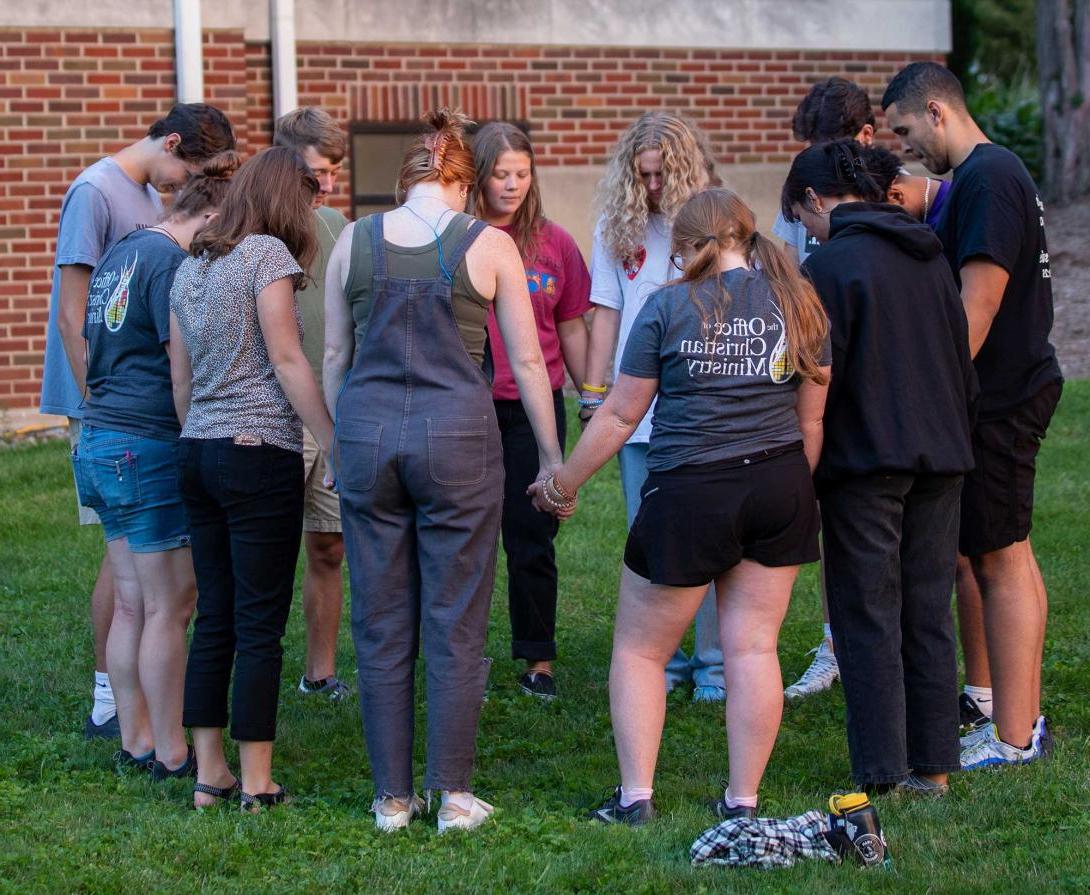 Group of students standing in a circle praying
